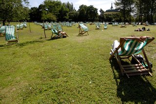 Oamenii care stau pe scaune pe iarbă într-un parc într-o zi însorită