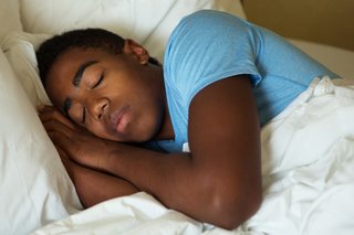 Un băiat adolescent adormit în pat