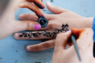Un tatuaj floral cu henna neagră este pictat pe o mână