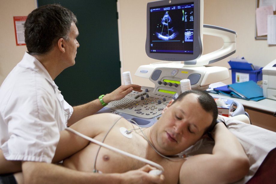 Un bărbat care are o ecocardiogramă, cu senzori atașați la piept și o imagine pe un monitor